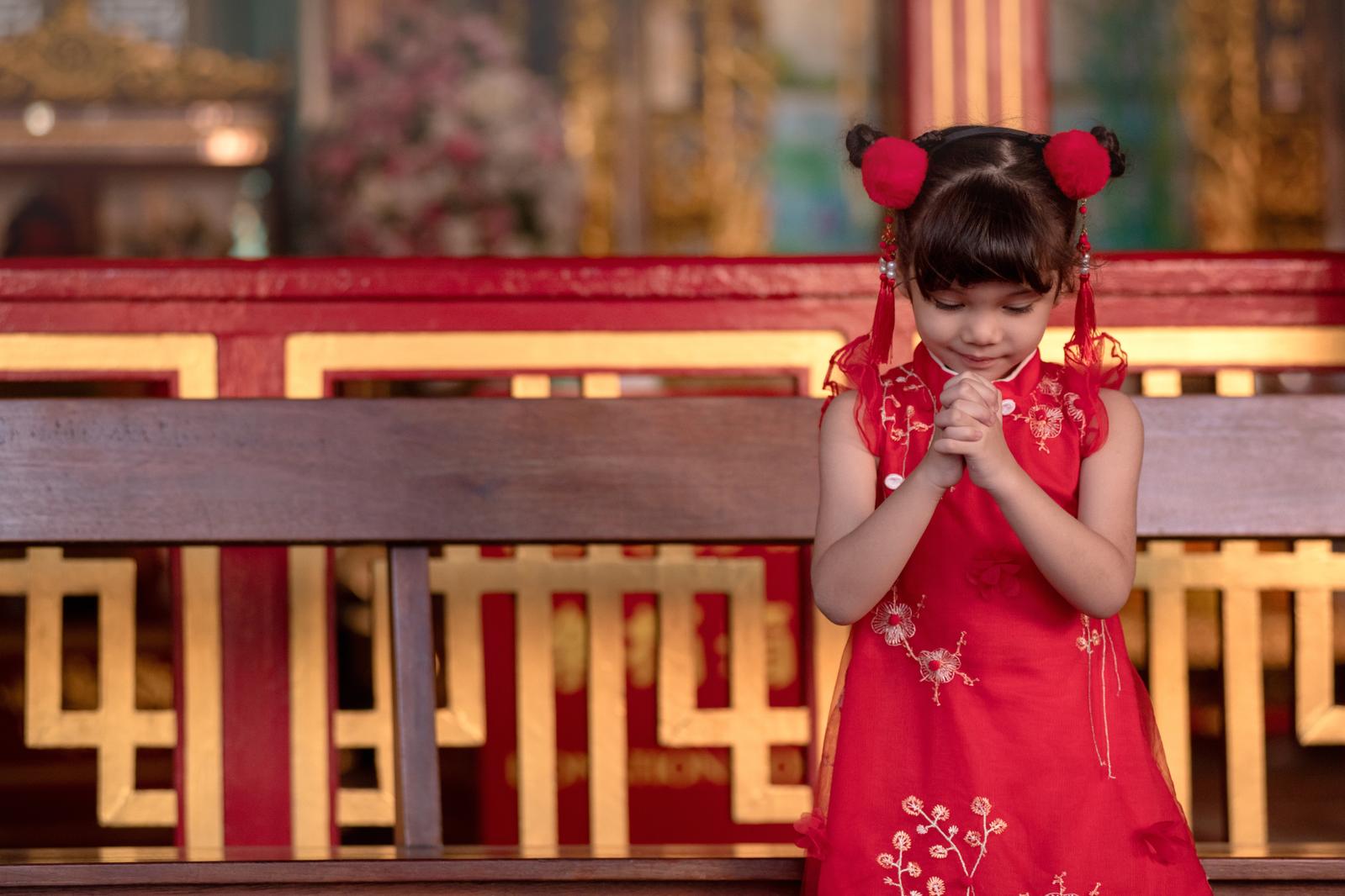 A girl in a red dress with clasped hands