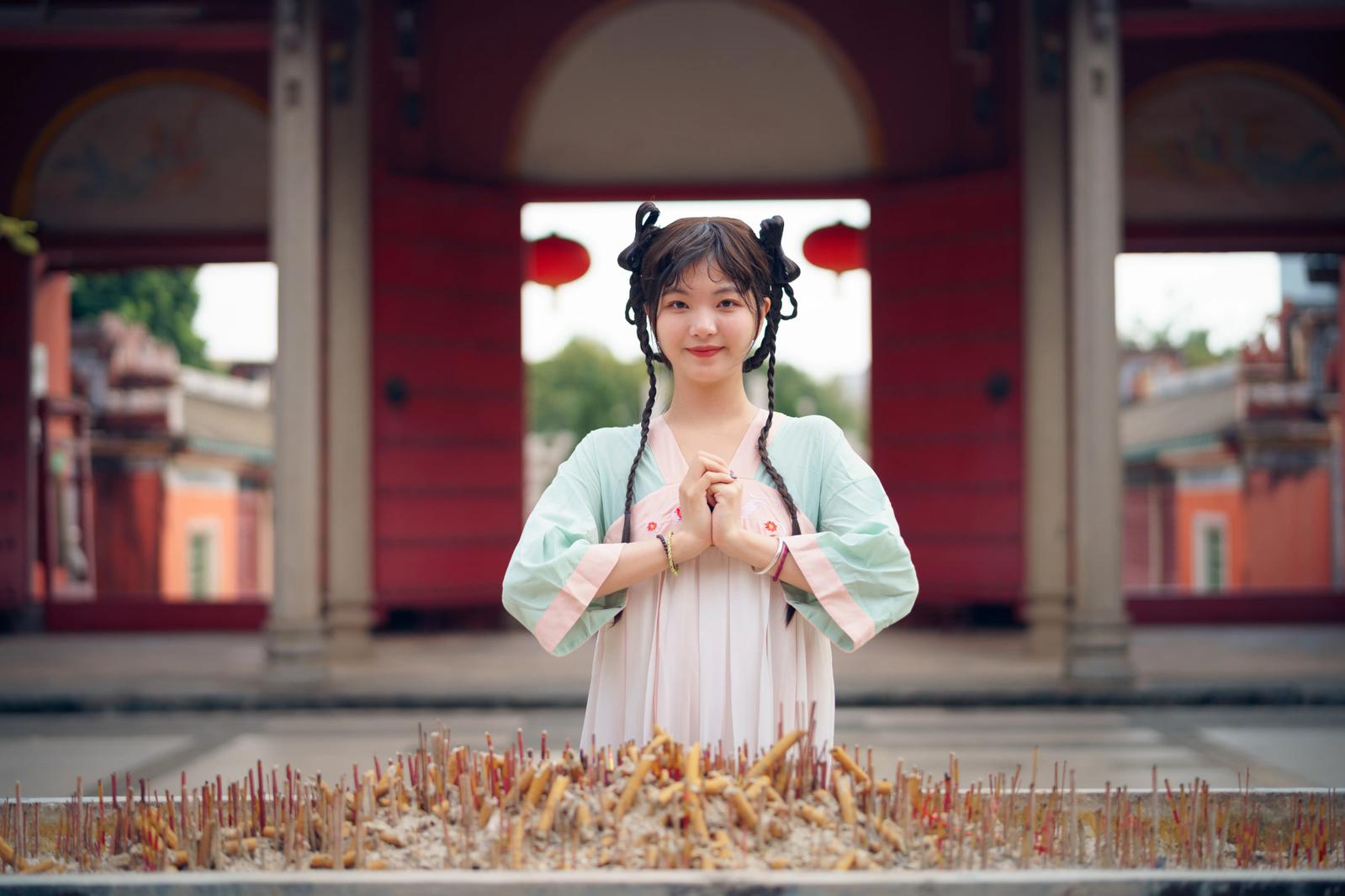 A Chinese woman with her hands clasped in front her heart, showing her sincere gratitude.