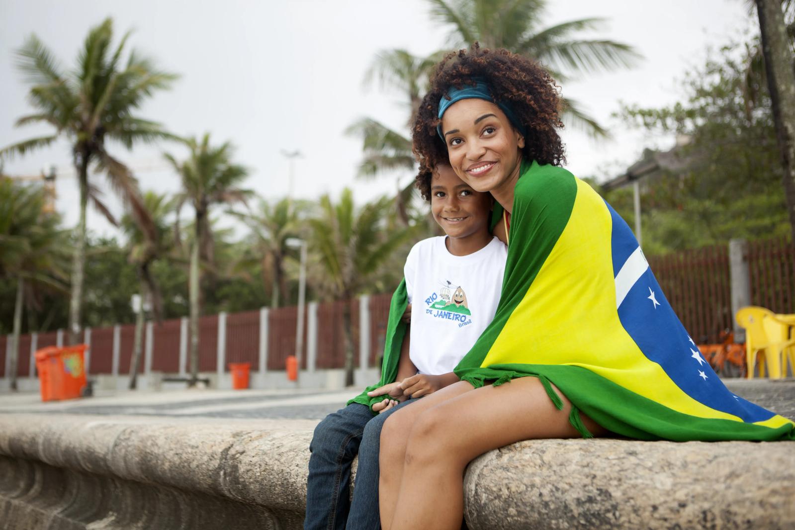 A Brazilian woman and a child sitting down, wrapped in a flag.