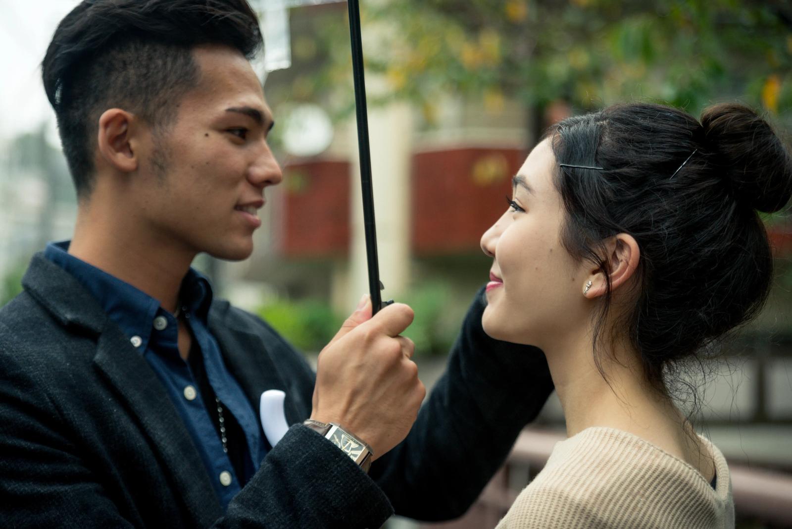 A man and woman under an umbrella, looking into each other's eyes—the moment of first love!