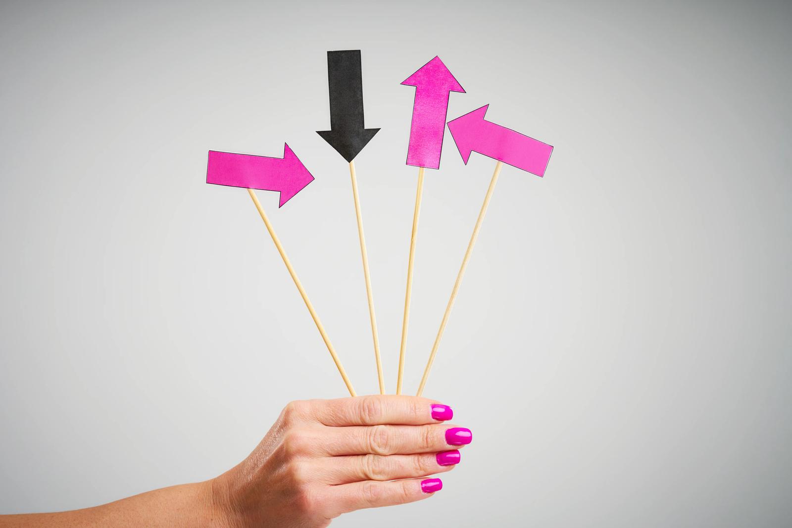 A female hand holding four colored arrows, intended to represent the four main tones of Mandarin Chinese.