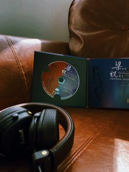 A pair of headphones on a leather chair next to a Chinese album.