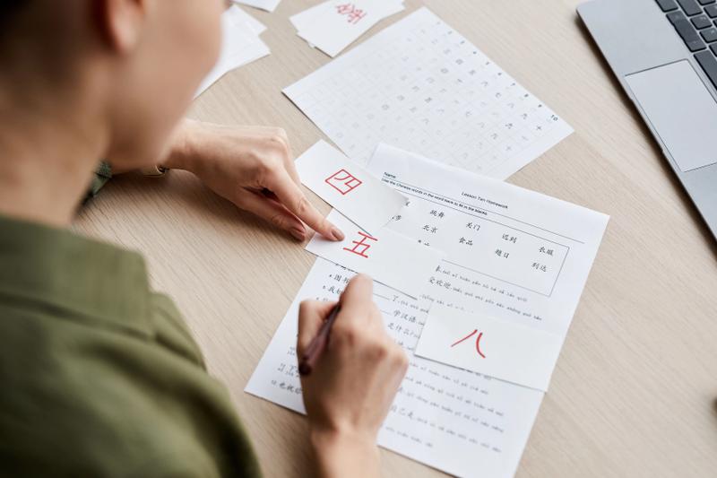 A man practicing writing Chinese numbers on graph paper.