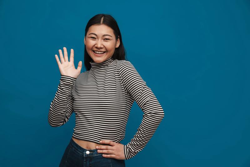 A Japanese woman waving, to say "hello".