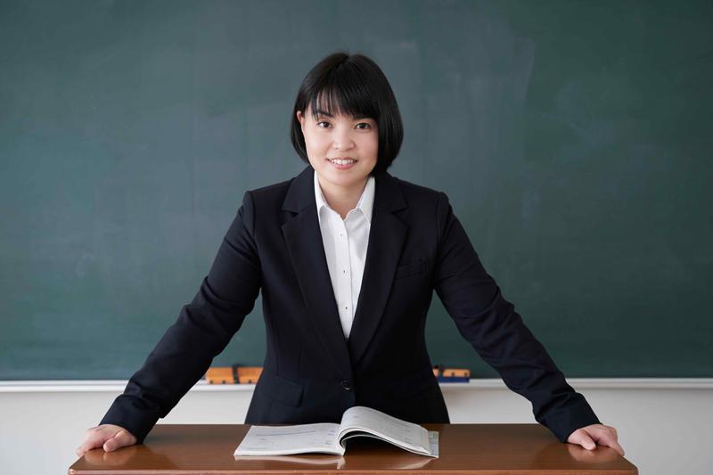 A young school teacher standing in front of a desk, perhaps about to give a lesson about the most important Korean grammar points