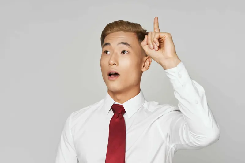 An attractive Korean man raising his hand, perhaps to make the argument it isn't hard to learn Korean.