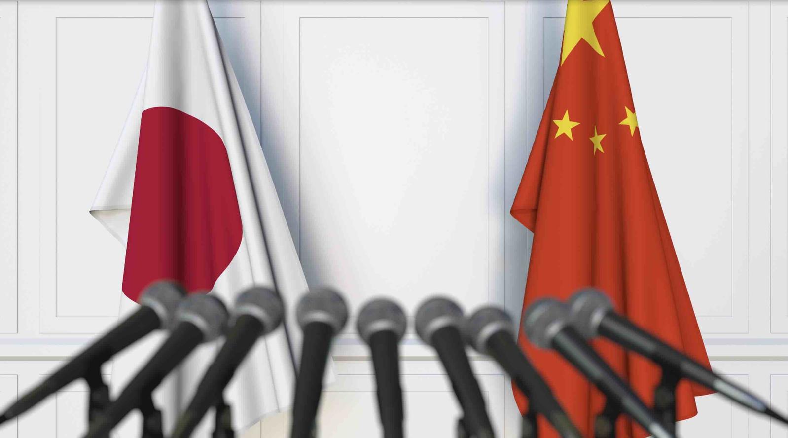 An image of a Japanese and Chinese flag at a press conference.