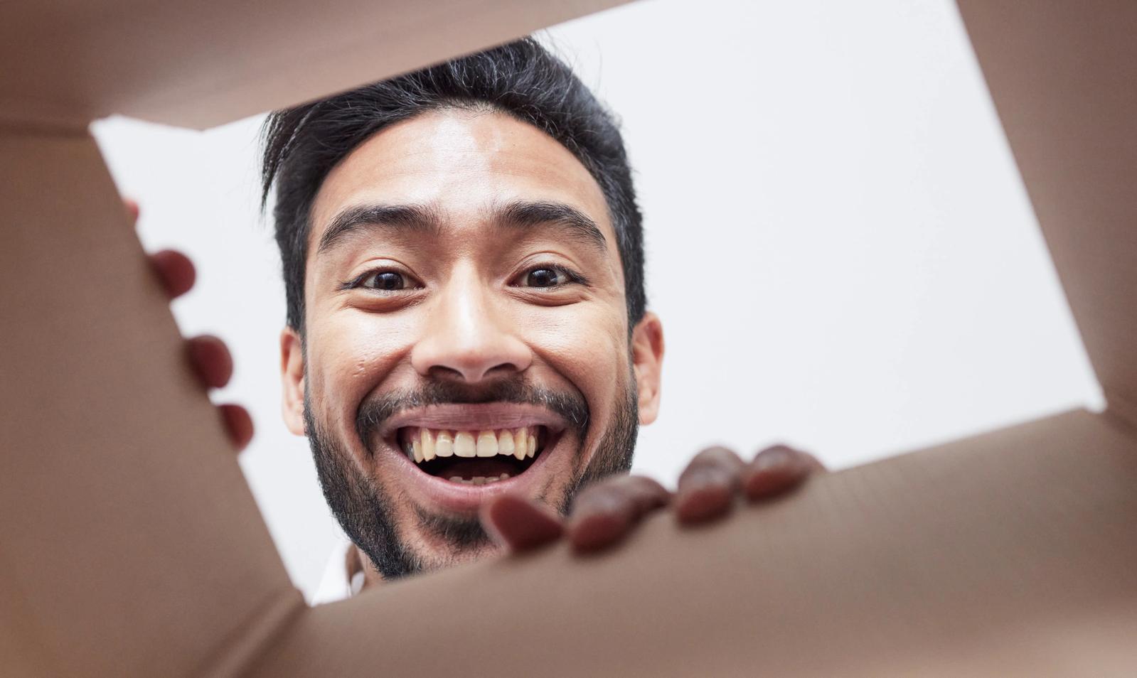 An excited-looking man looking into a box to see what's there.