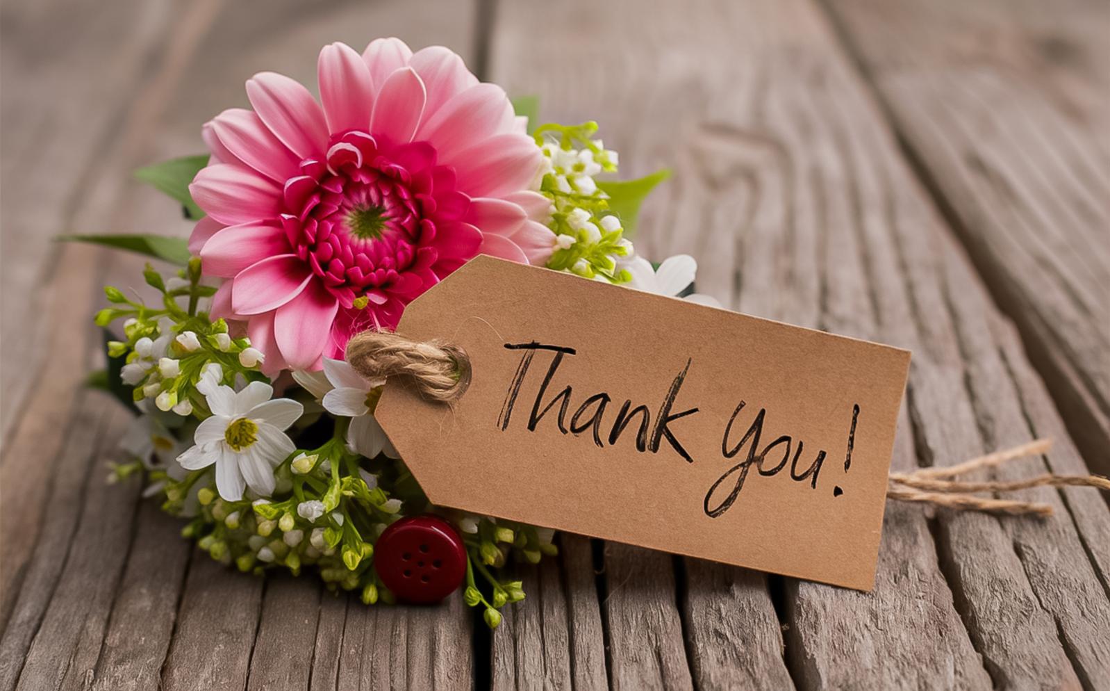 Flower with a thank you note on a wooden floor