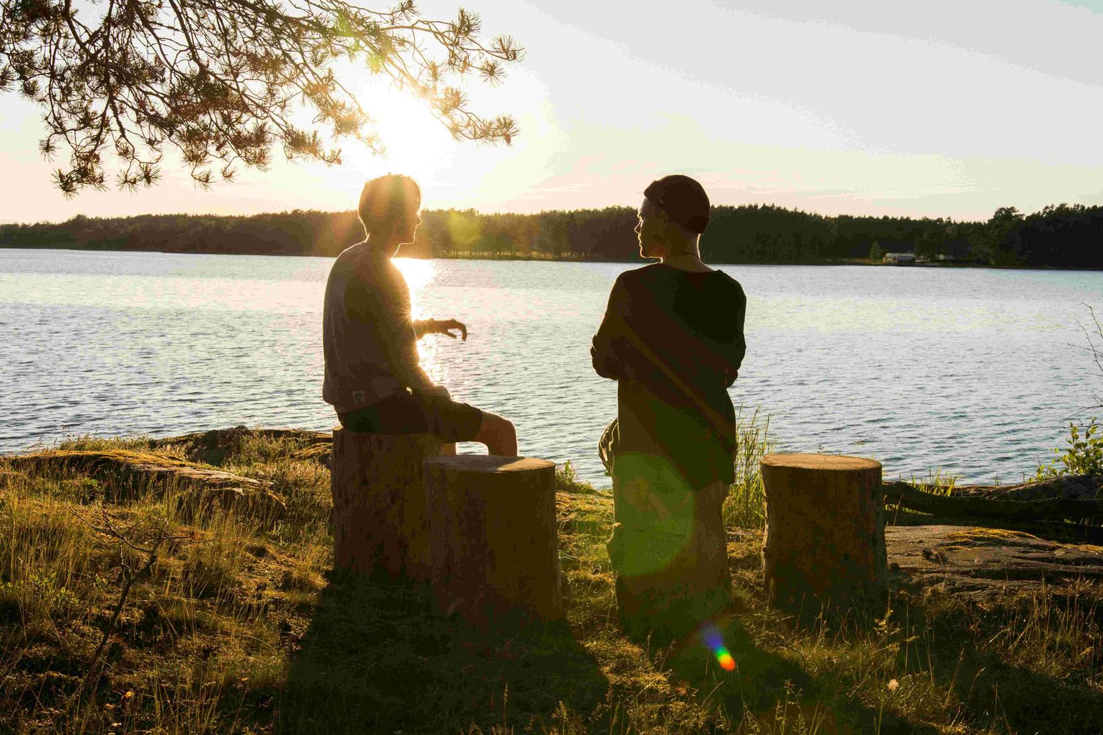 Two people chatting by a lake