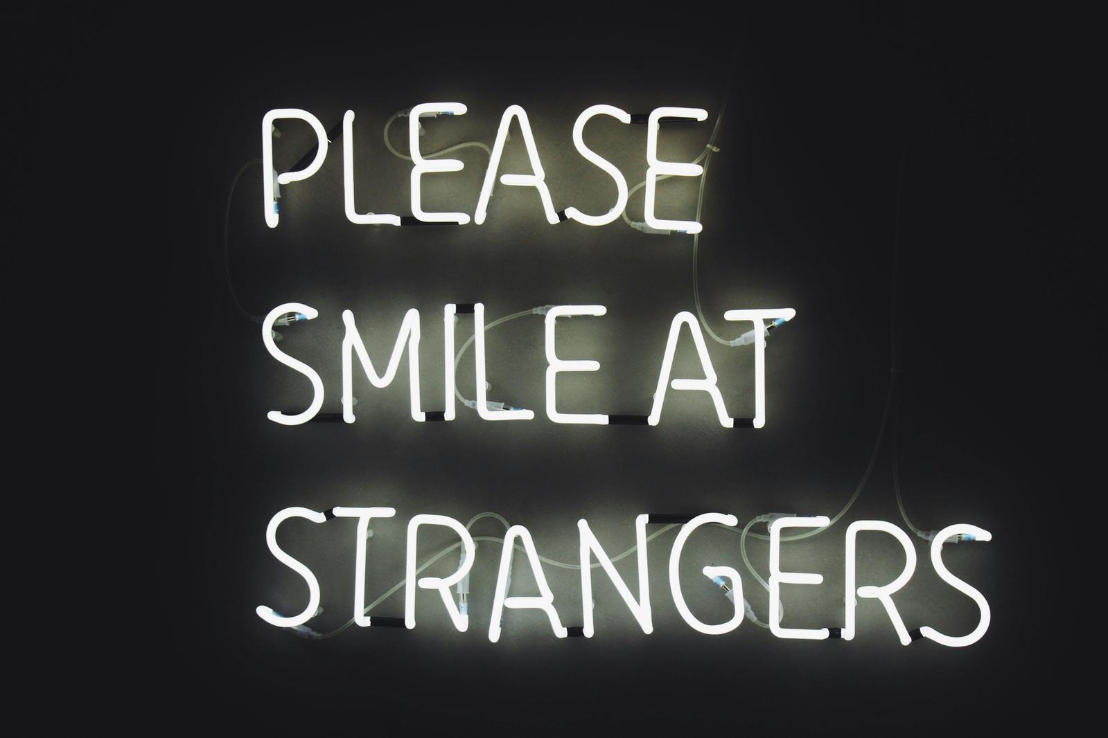 'Please smile at strangers' in neon lights (Unsplash: Haut Risque)