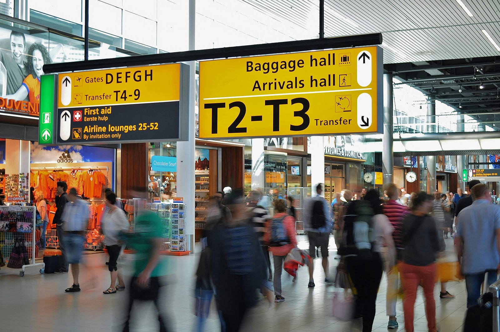 A photograph taken in an airport, showing some direction signs with information about gates and terminals