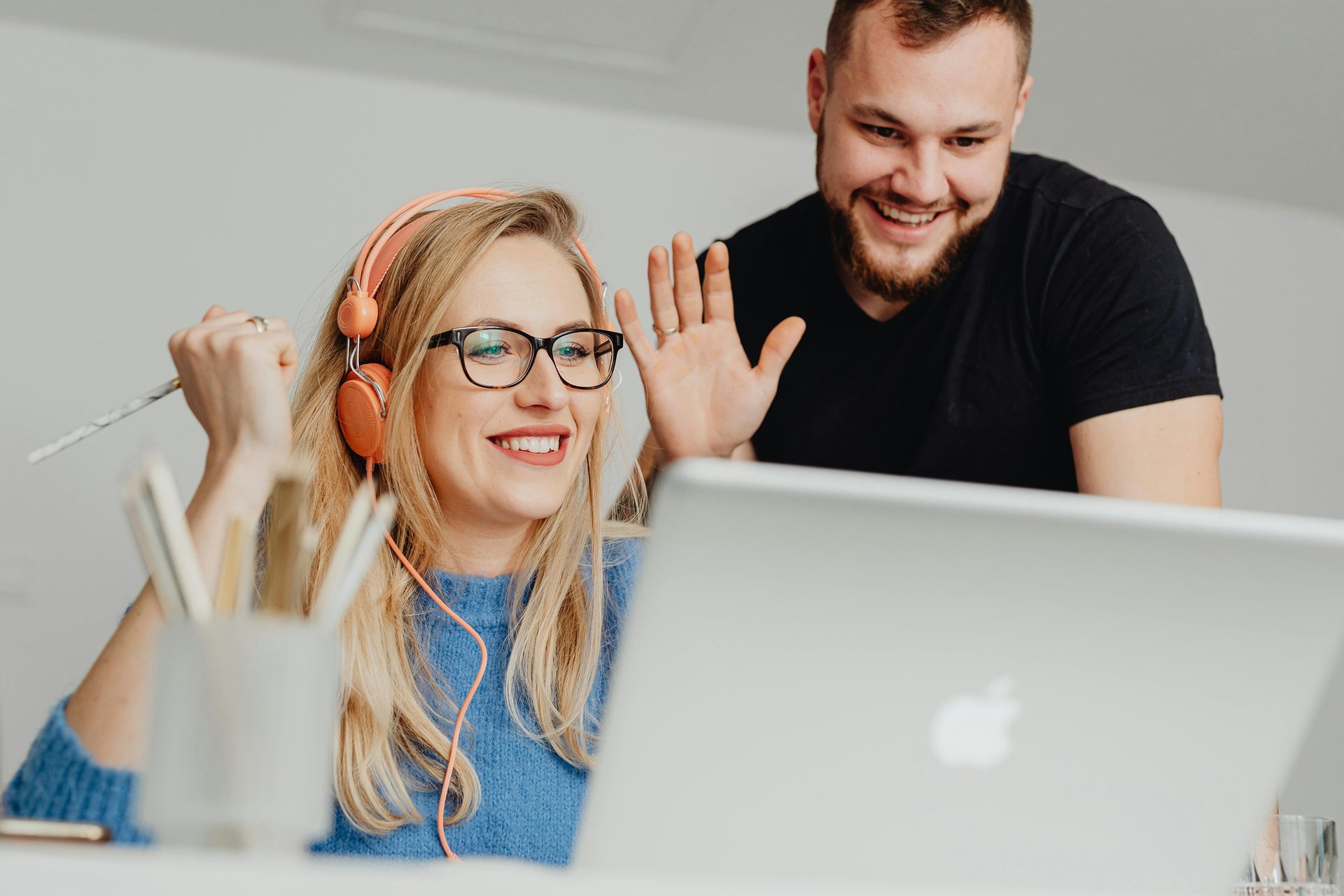 A couple of friends waving to greet someone they miss on the webcam, whom they are finally getting to talk to