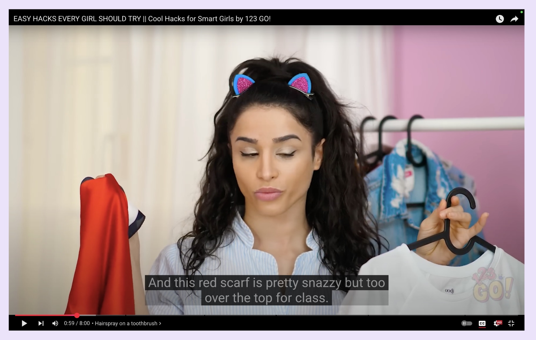 A screenshot of a woman on YouTube holding up a red scarf.