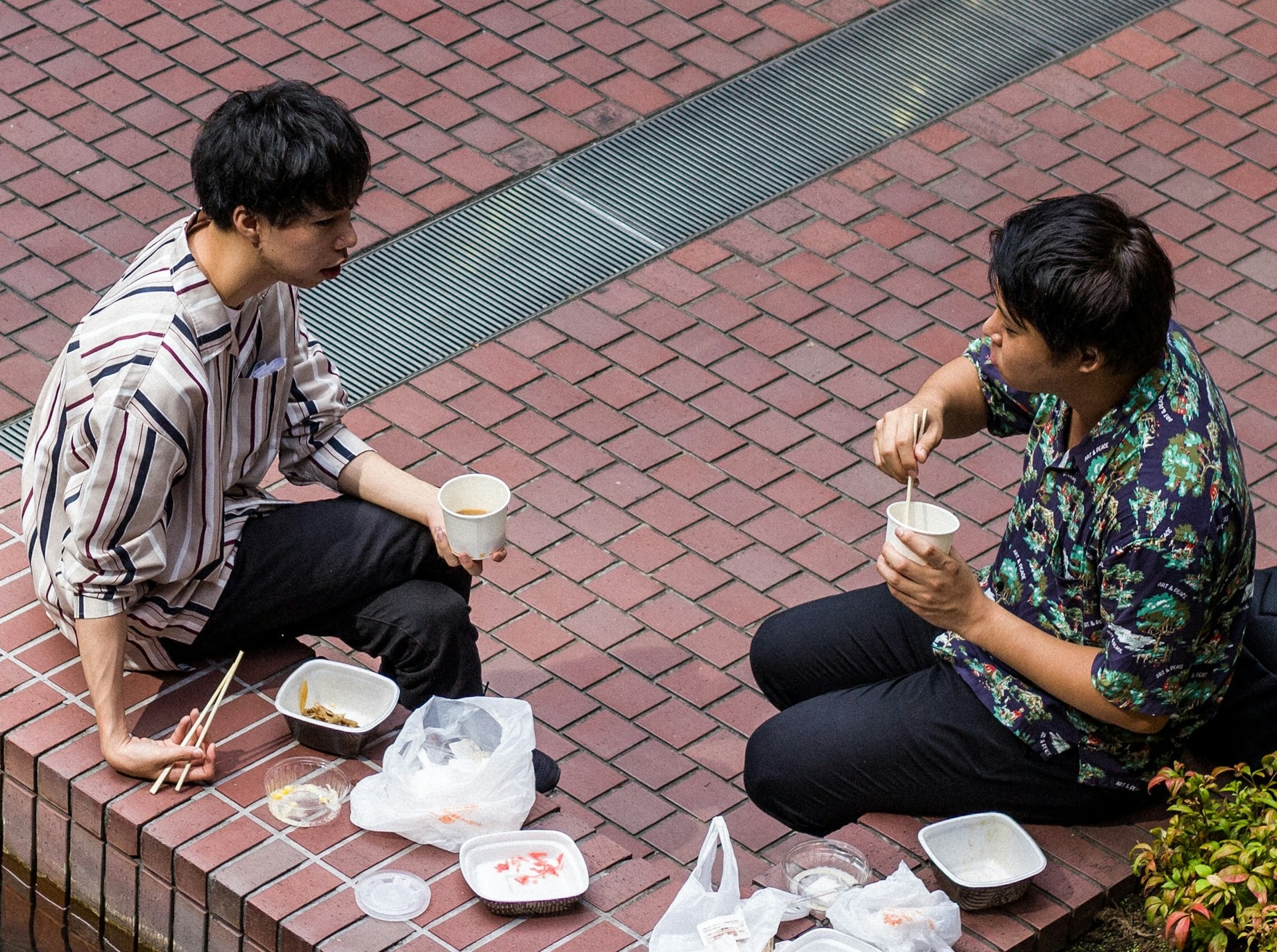 A couple of dudes sitting by the side of the street eating lunch; they definitely aren't using honorific language with each other